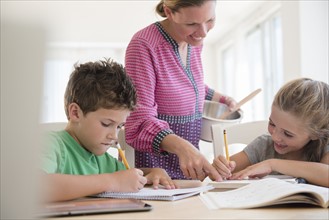 Mother assisting children (6-7, 8-9) with homework