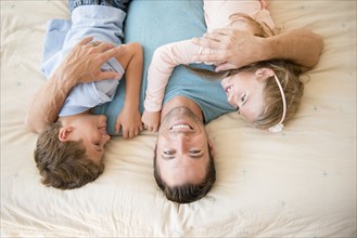 Father lying down with son (8-9) and daughter (6-7)