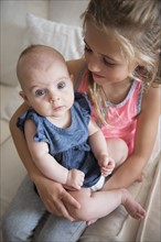 Young girl (6-7) holding baby sister (2-5 months)
