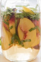 Slices of peach and chopped basil in pitcher