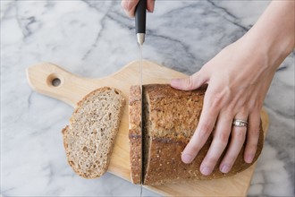 Close-up of woman's hands cutting bread