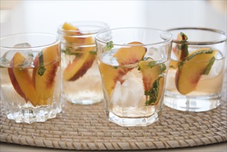 Cocktail with slices of peaches in drinking glass
