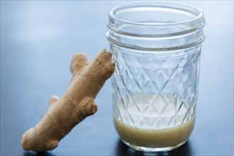 Ginger and homemade juice in drinking glass