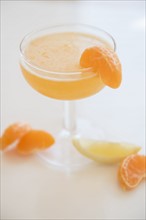 Cocktail in drinking glass and slices of tangerines and lemon