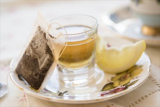 Whiskey in shot glass, slice of lemon and teabag on saucer