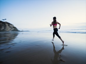 Woman wearing sports clothes running on beach