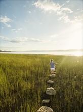 Small girl (4-5) walking on stepping stones in meadow