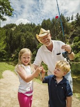 Small girl and boy (4-5) fishing with grandfather
