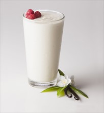 Vanilla smoothie in glass decorated with raspberry