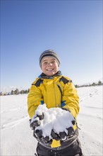 Portrait of boy (8-9) holding snow