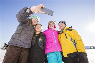 Children (8-9, 10-11) taking selfie in winter