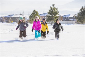 Children (8-9, 10-11) running in snow