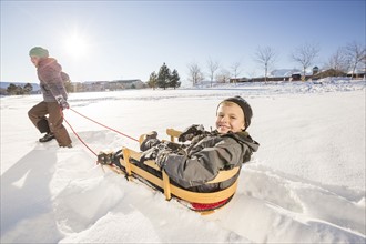 Children (8-9) playing with sled in snow