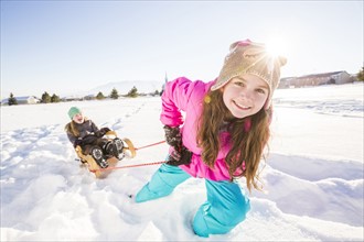Children (8-9, 10-11) playing with sled in snow