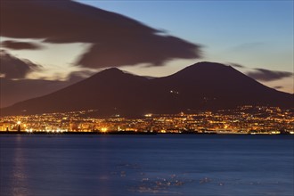 Illuminated city between sea and Mount Vesuvius