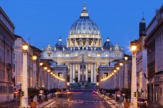 Illuminated St. Peter's Basilica with asphalt road in foreground at dusk