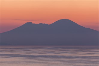 Silhouette of mountains with sea in foreground at sunset