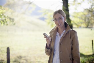 Smiling woman in beige coat with mobile phone