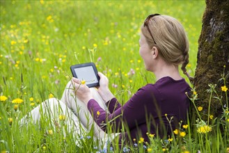 Woman using e-reader in meadow