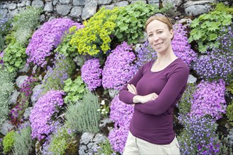 Smiling woman standing against flowerbed