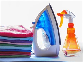 Iron, spray bottle and pile of clean laundry