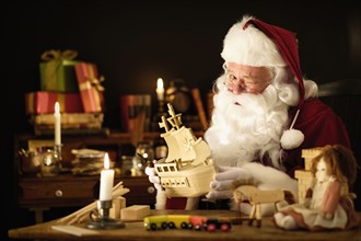 Santa Claus making wooden toy and winking.