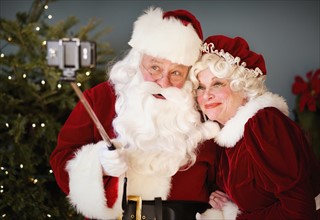 Santa and Mrs. Santa taking selfie with monopod.