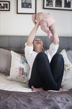 Mother playing with baby daughter (2-5 months) in bedroom.