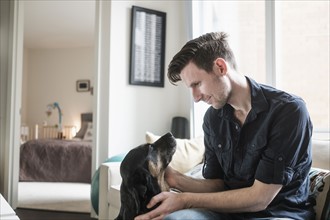 Man playing with dog in living room.