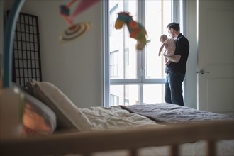 Father looking through window with daughter (2-5 months).