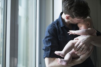 Father standing by window with daughter (2-5 months).