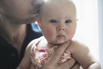 Father kissing daughter's (2-5 months) head.