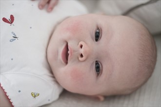 Cute baby girl (2-5 months) lying on bed.