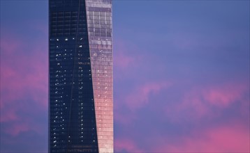 Part of One World Trade Center against dramatic sky at dusk. USA, New York, New York City.