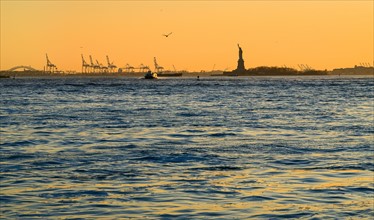 Silhouette of Statue of Liberty at sunset. USA, New York, New York City.