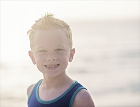 Portrait of boy (6-7) in blue tank top at beach