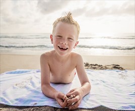 Portrait of boy (6-7) and girl (4-5) lying on beach laughing