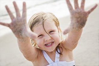 Girl (4-5) on beach showing her dirty hands