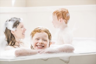 Mother and children (2-3, 4-5) having bubble bath