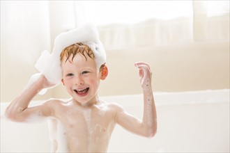 Smiling boy (2-3) having bubble bath