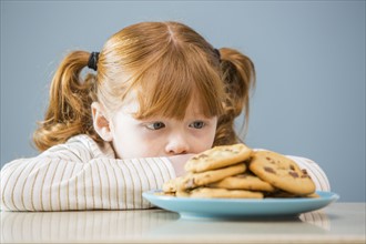 Girl (4 -5) looking on plate of cookies