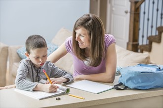 Mother helping son (6-7) doing homework