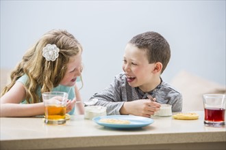 Smiling children (6-7, 8-9) eating pudding at table