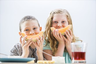 Children (6-7, 8-9) eating cantaloupe for breakfast