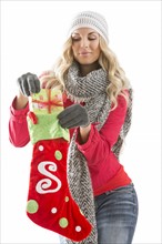 Young woman taking out present from Christmas stocking