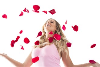 Young woman throwing up rose petals above head