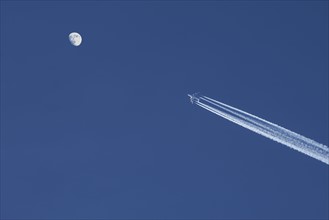 Airplane against blue sky with moon