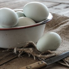 Fresh eggs in bowl on wooden table.