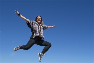 Young woman jumping against clear sky.