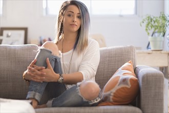 Confident young woman sitting on sofa.